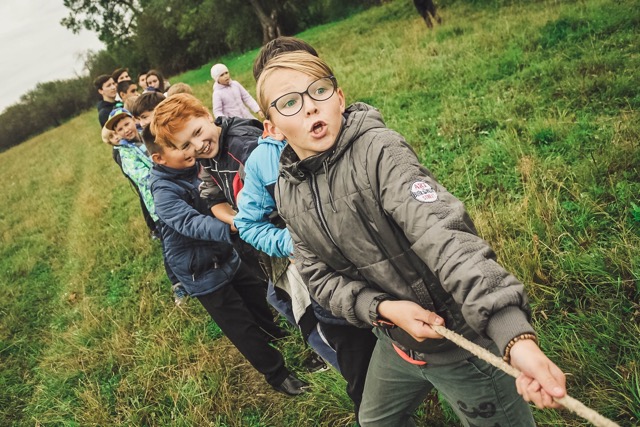 A group of students succeed in successful teamwork while playing tug of war on a school playground.